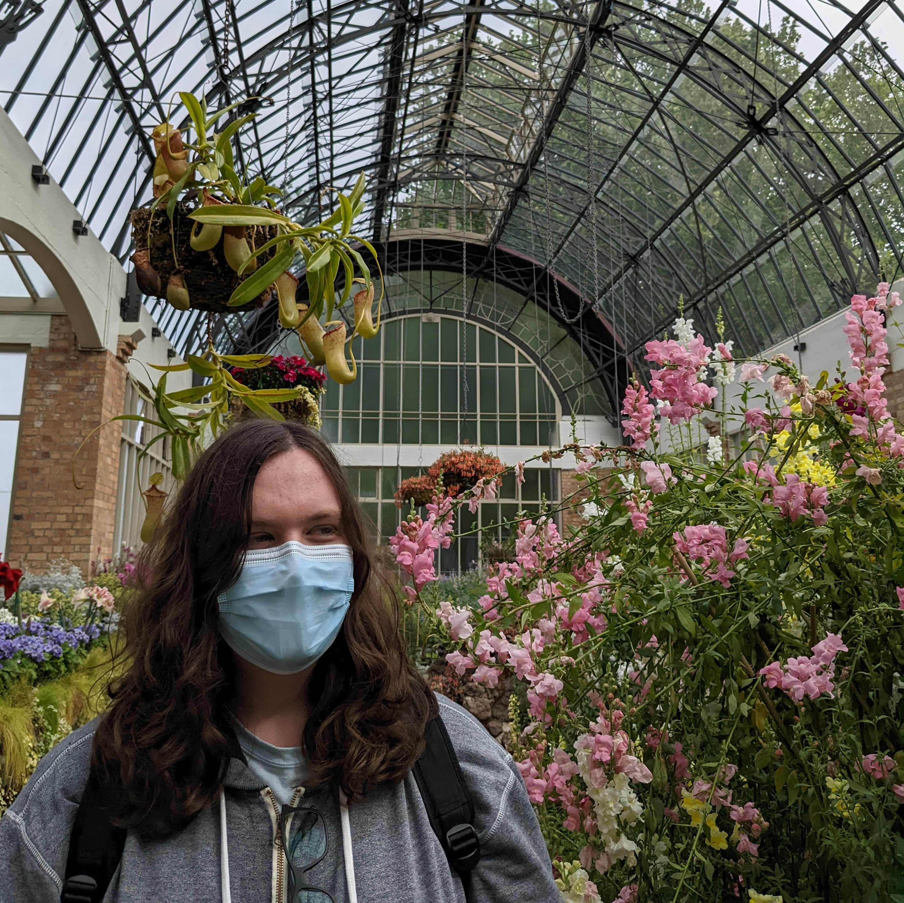 A photo of me standing next to some flowers in a greenhouse